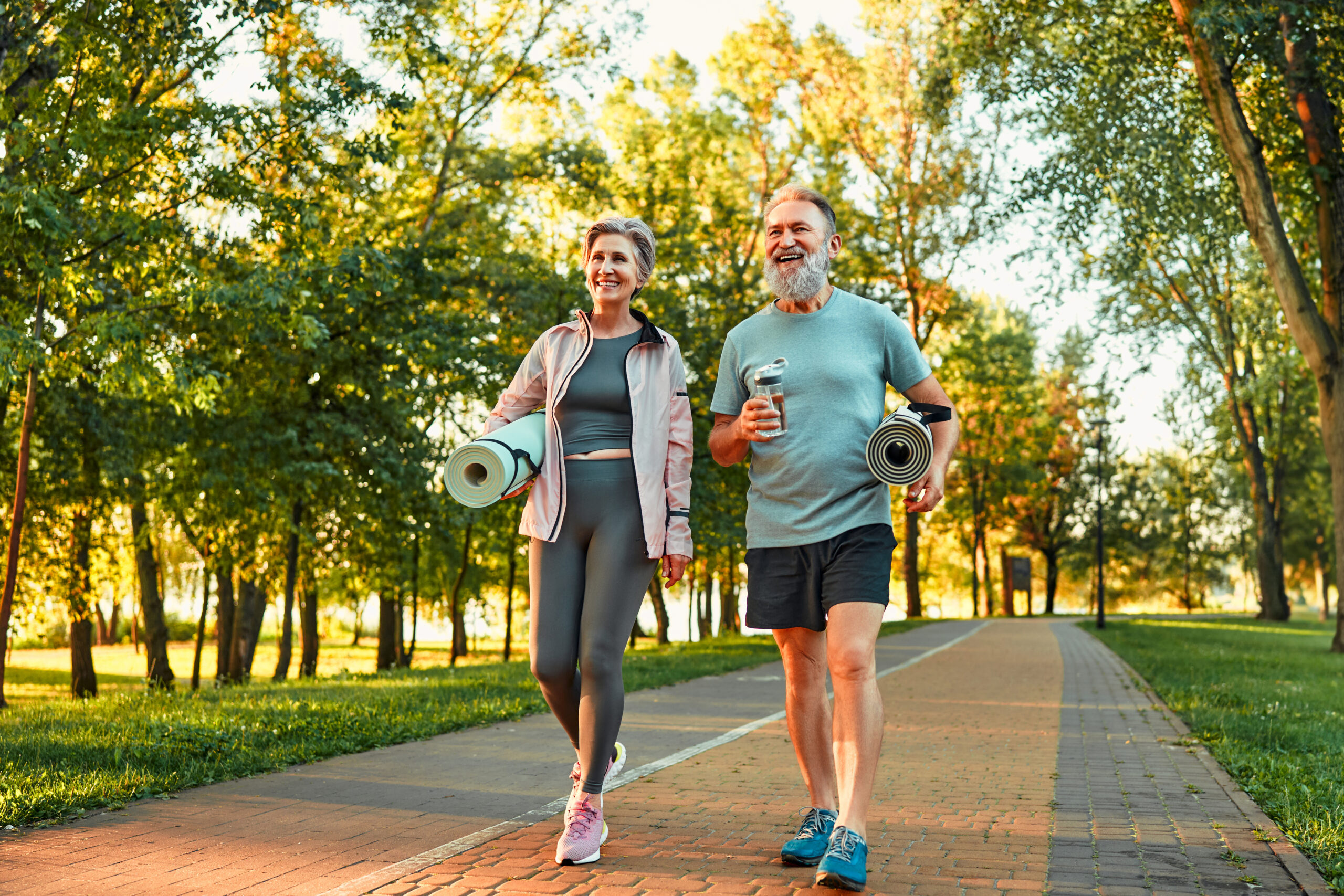 A couple jogging outside on a sidewalk during a sunny day