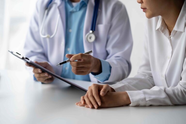 A physician offering concierge medicine services explains medical notes on a clipboard to a patient.